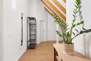 A hallway with a wooden bench, a potted plant, and a black shelving unit. - Apartment 'Holiday  Mühlenblick Jg' with Balcony (Löffingen)