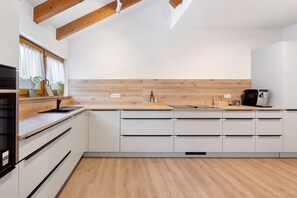 A modern kitchen with wooden beams, white cabinets, a wooden countertop, and a built-in oven. - Apartment 'Holiday  Mühlenblick Jg' with Balcony (Löffingen)