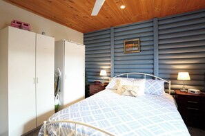 A bedroom with a bed, two bedside tables with lamps, a wardrobe, and a wall-mounted picture.
