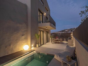 Una piscina al aire libre, sombrillas, sillones reclinables de piscina