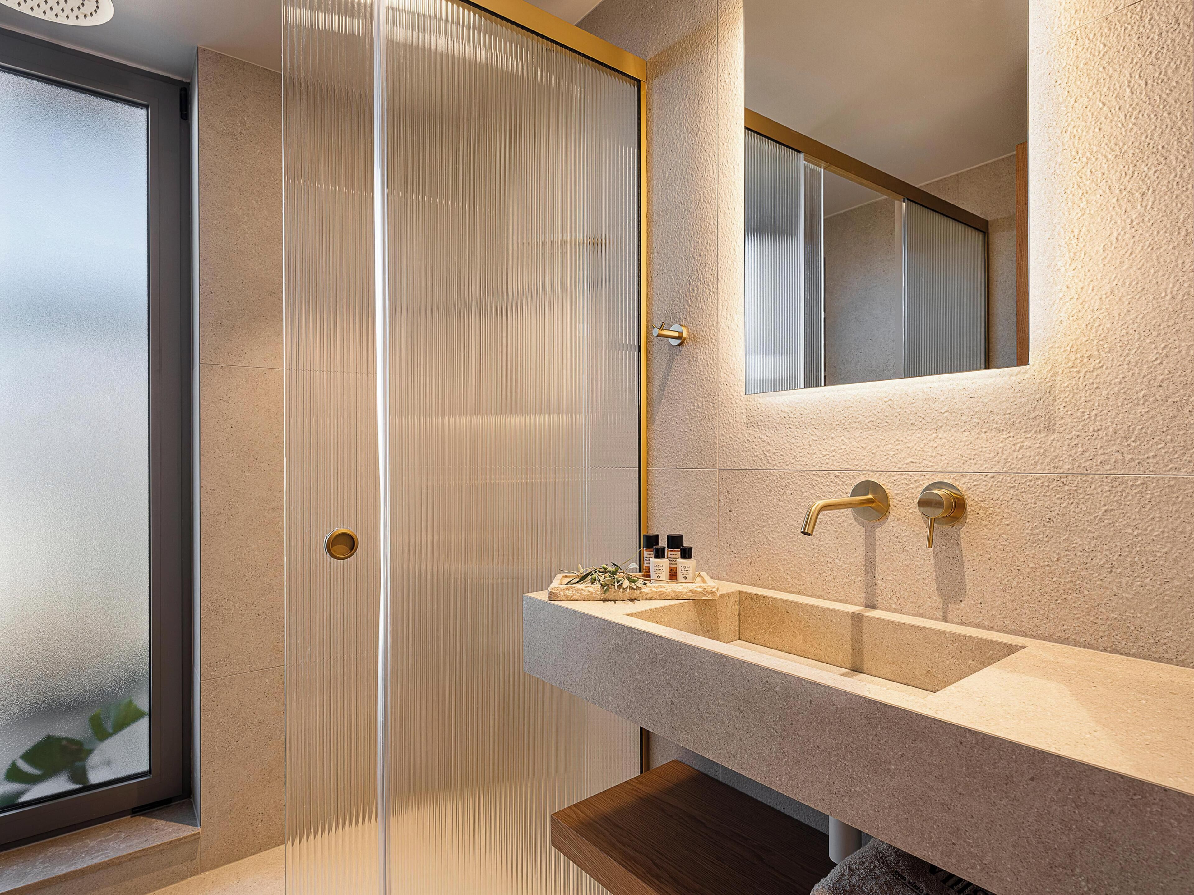 A modern bathroom with a large mirror, a sink, and a shower area.