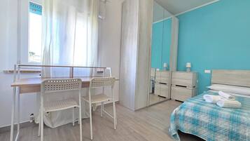 Un dormitorio con cama, escritorio, sillas, armario y espejo.