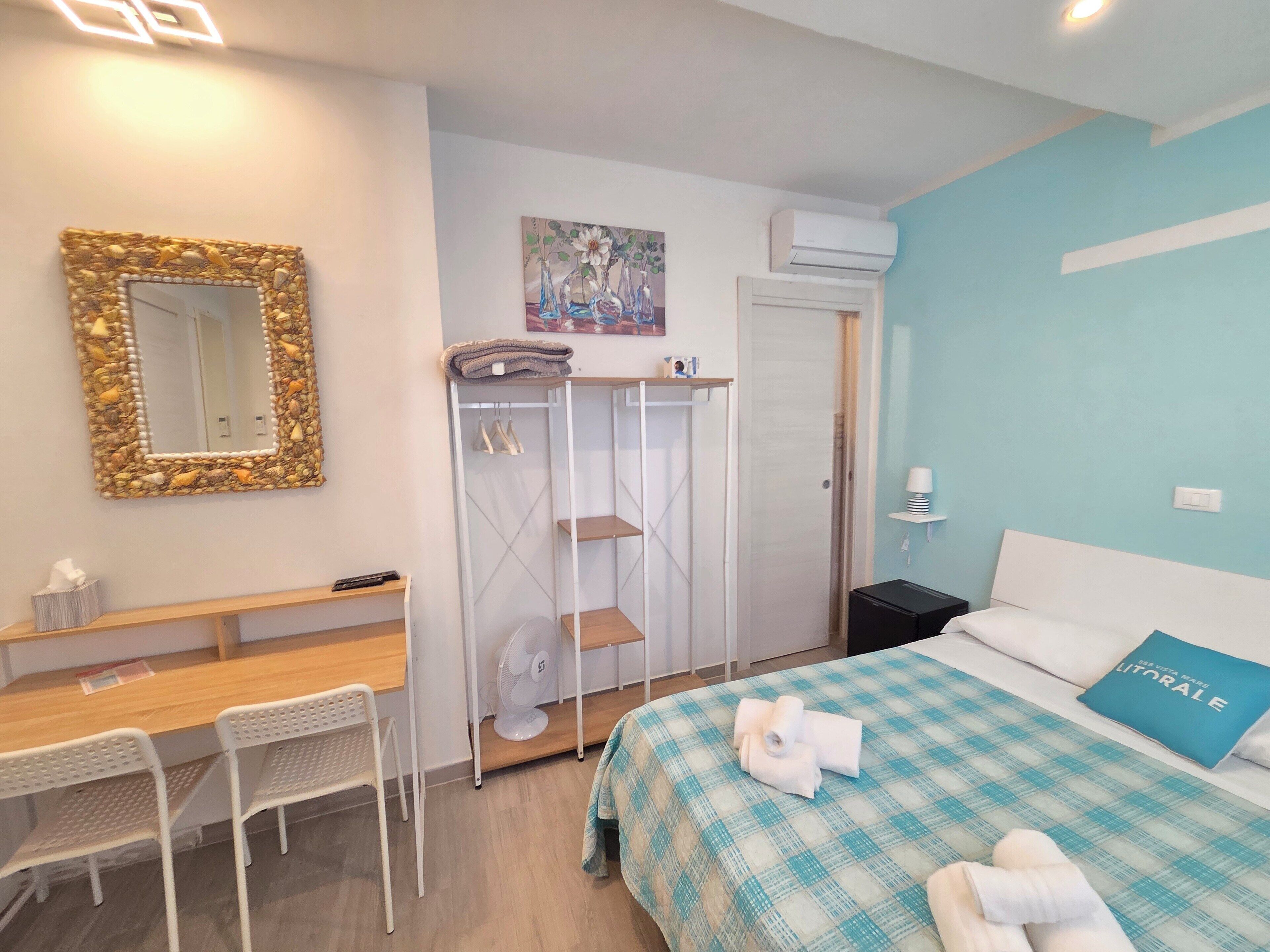 A bedroom with a bed, a desk, a chair, a wardrobe, and a mirror.
