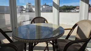 A glass-top table with wicker chairs on a balcony with large windows. - B&B Litoranea 80 (Follonica)