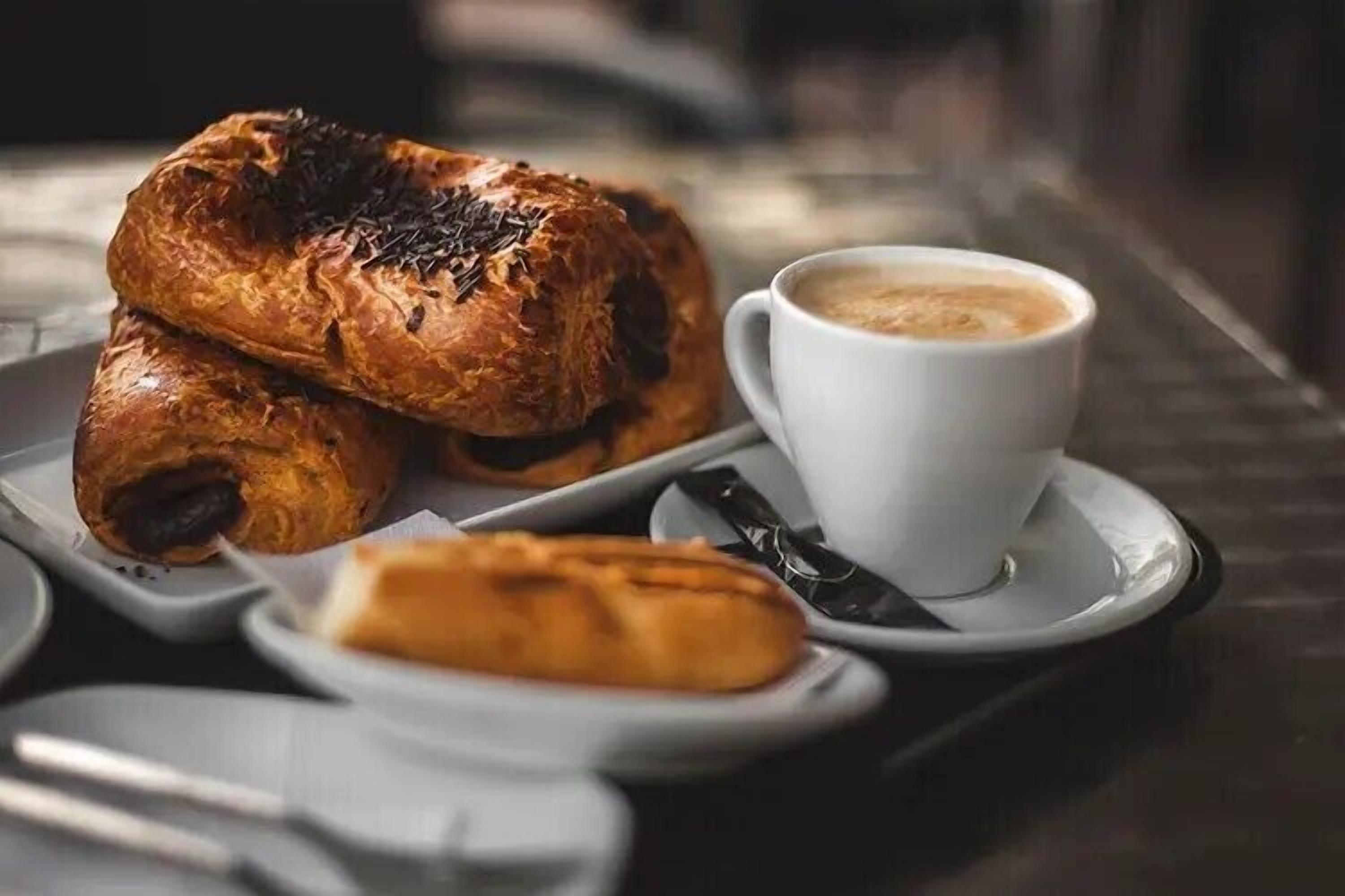 Una bandeja con pasteles y una taza de café sobre una mesa.