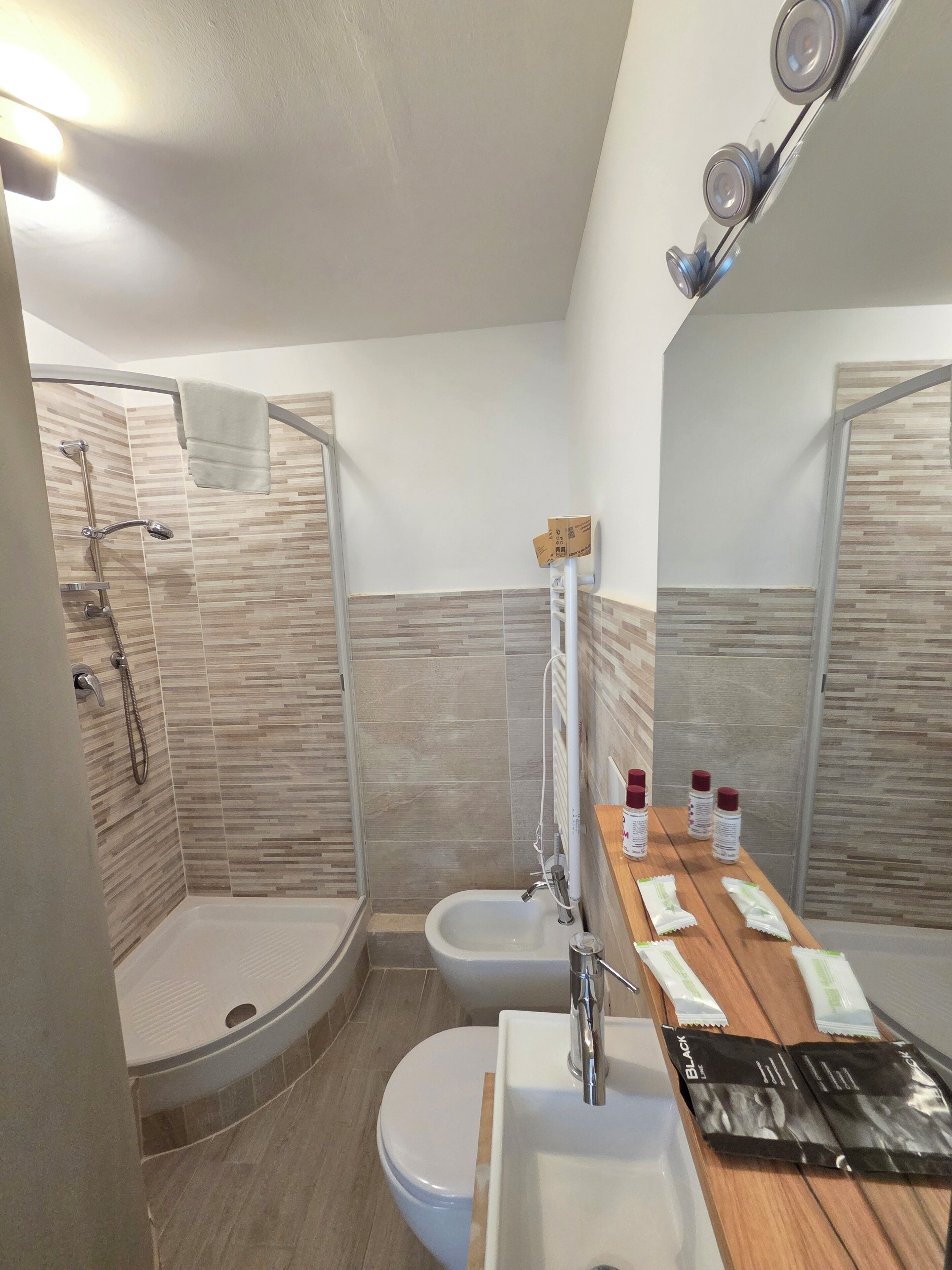 Une salle de bain moderne équipée d’une douche, de toilettes, d’un bidet et d’un meuble-lavabo avec des articles de toilette.