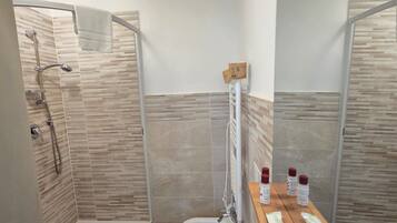 Une salle de bain moderne équipée d’une douche, de toilettes, d’un bidet et d’un meuble-lavabo avec des articles de toilette.