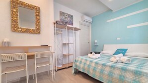 A hotel room with a bed, a desk, two chairs, a wardrobe, and a mirror with a stone frame. - B&B Litoranea 80 (Follonica)