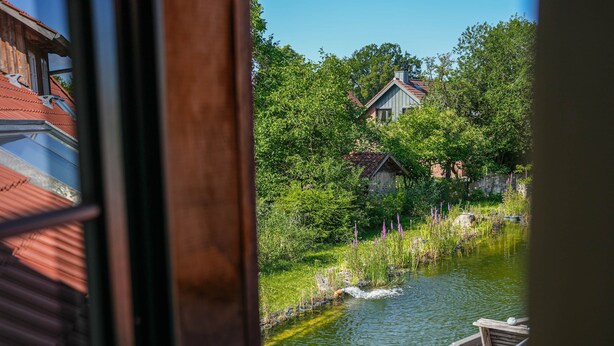 Vista de un río con un muelle de madera y una casa al fondo.