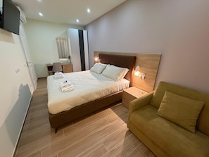 A neatly arranged bedroom with a bed, bedside table, and a sofa. - Maya Casa (Rome)