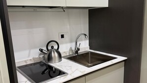 Uma cozinha moderna com chaleira de aço inoxidável, uma pia e bancada de mármore.