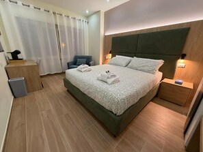 A modern bedroom with a large bed, a bedside table, a chair, a desk, and a trash bin. - Maya Casa (Rome)