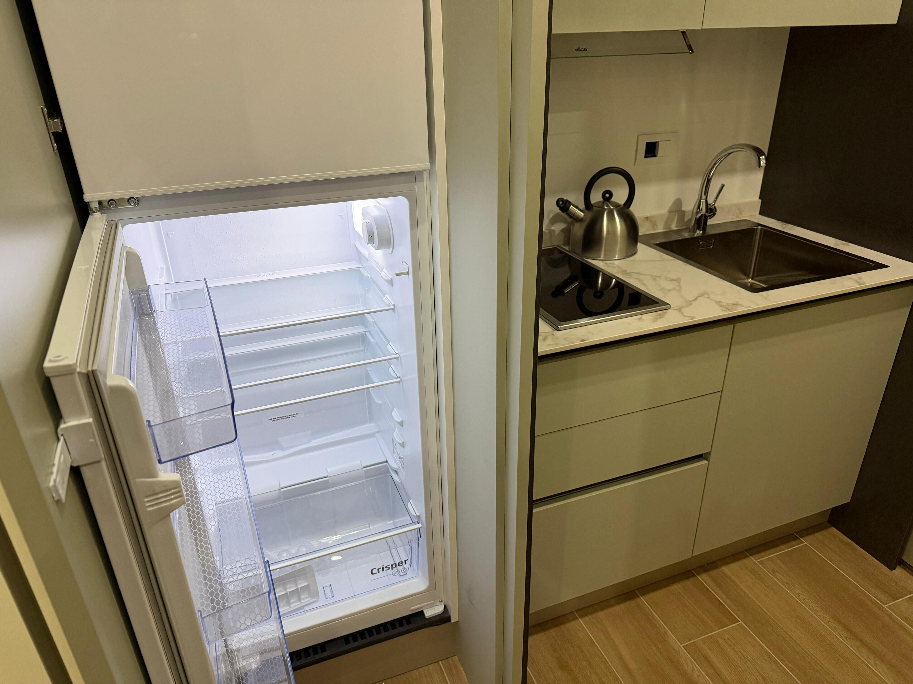 A kitchen with a built-in refrigerator, a kettle, and a sink.