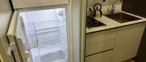A kitchen with a built-in refrigerator, a kettle, and a sink.