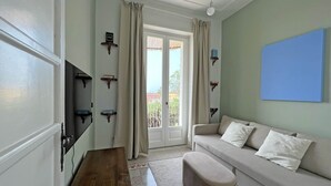 Een kamer met een bank, een poef, een houten tafel en een televisie op een plank.