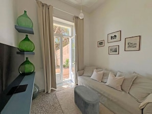 A living room with a sofa, a coffee table, and a TV stand with green vases. - Villa Ipomea - Cielo & Terra (Salerno)