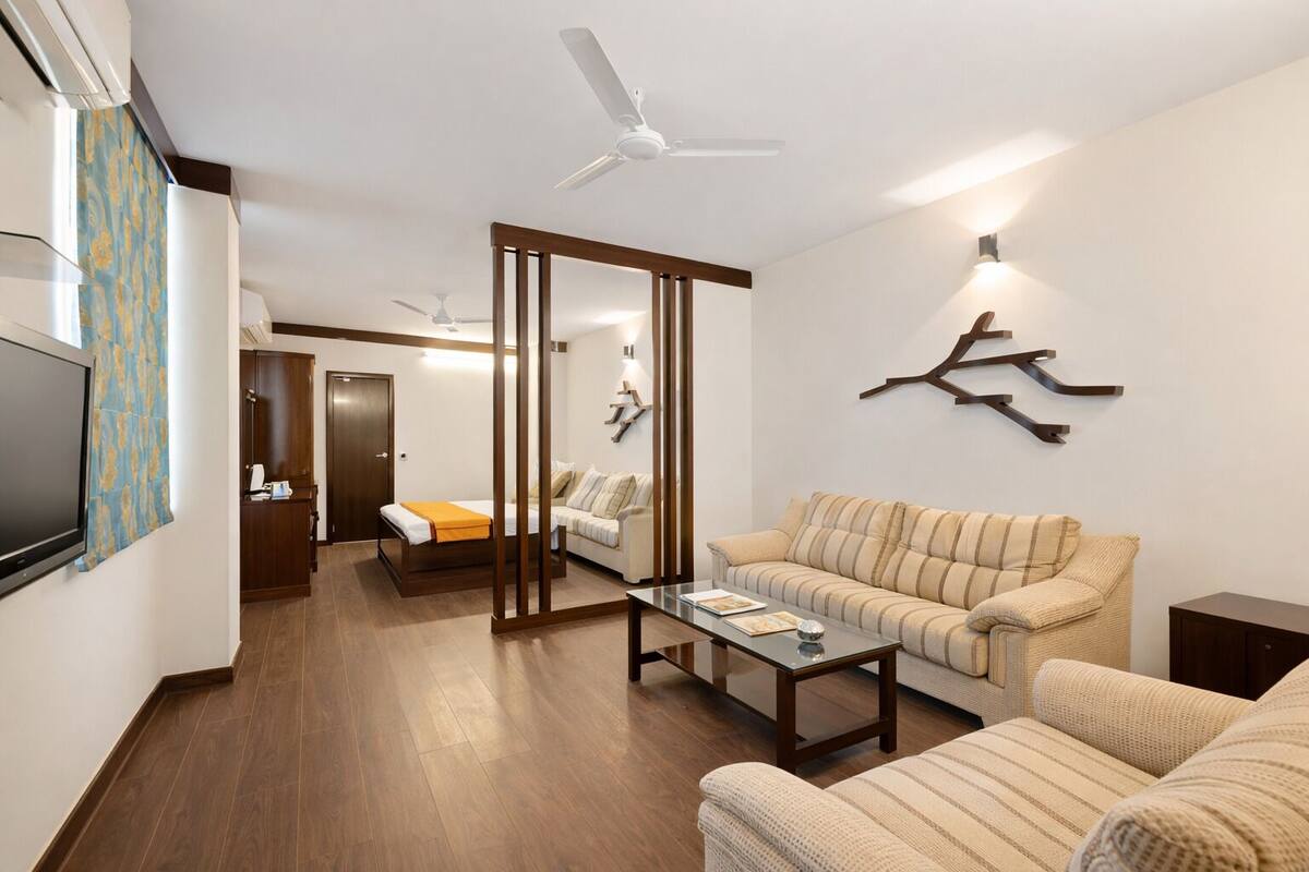 Una sala de estar moderna con sofá, una mesa de centro, televisor y cama con cabecera de madera.