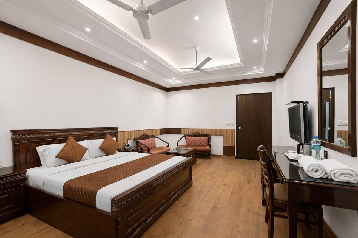 Una habitación de hotel con una cama grande, un escritorio con una silla, un televisor y un armario.