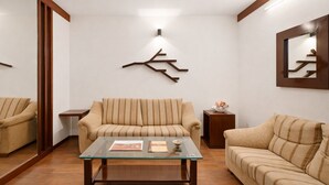 Un salón con una mesa de centro de vidrio, dos sofás, un aparador de madera y una lámpara fijada a la pared.