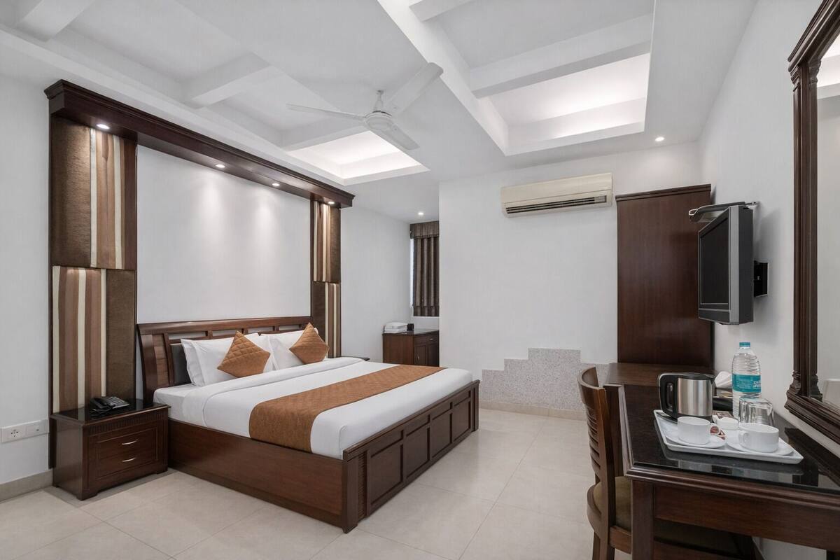 Habitación de hotel con una cama grande, un escritorio con una silla, un televisor y una botella de agua sobre la mesita.