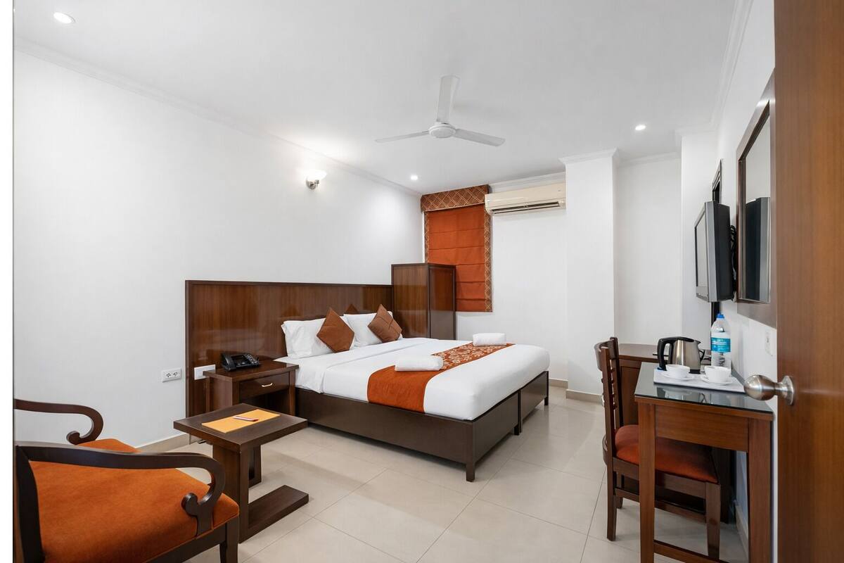 Una habitación de hotel con cama, mesita de noche, silla, escritorio y televisor.