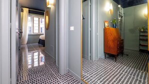 A hallway with patterned flooring, a mirror, a wooden dresser, and a window with curtains. - HT Vatican cozy rooms & apartments (Rome)