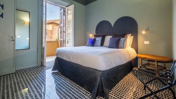 A bedroom with a bed, a chair, and a door leading to an outdoor area. - HT Vatican cozy rooms & apartments (Rome)