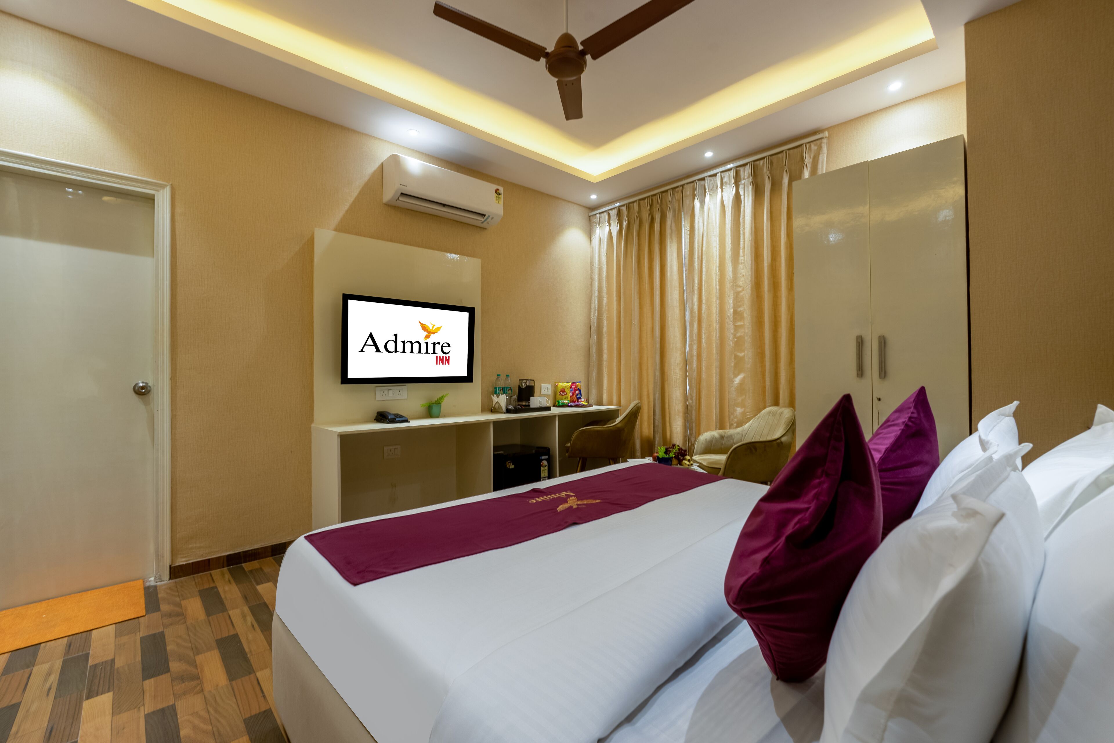 A hotel room with a bed, a desk, a television, and a wardrobe.