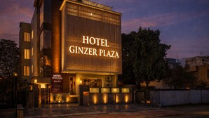 Ein modernes Hotelgebäude mit einer großen, beleuchteten Schrifttafel, auf der 'HOTEL GINZER PLAZA' steht.