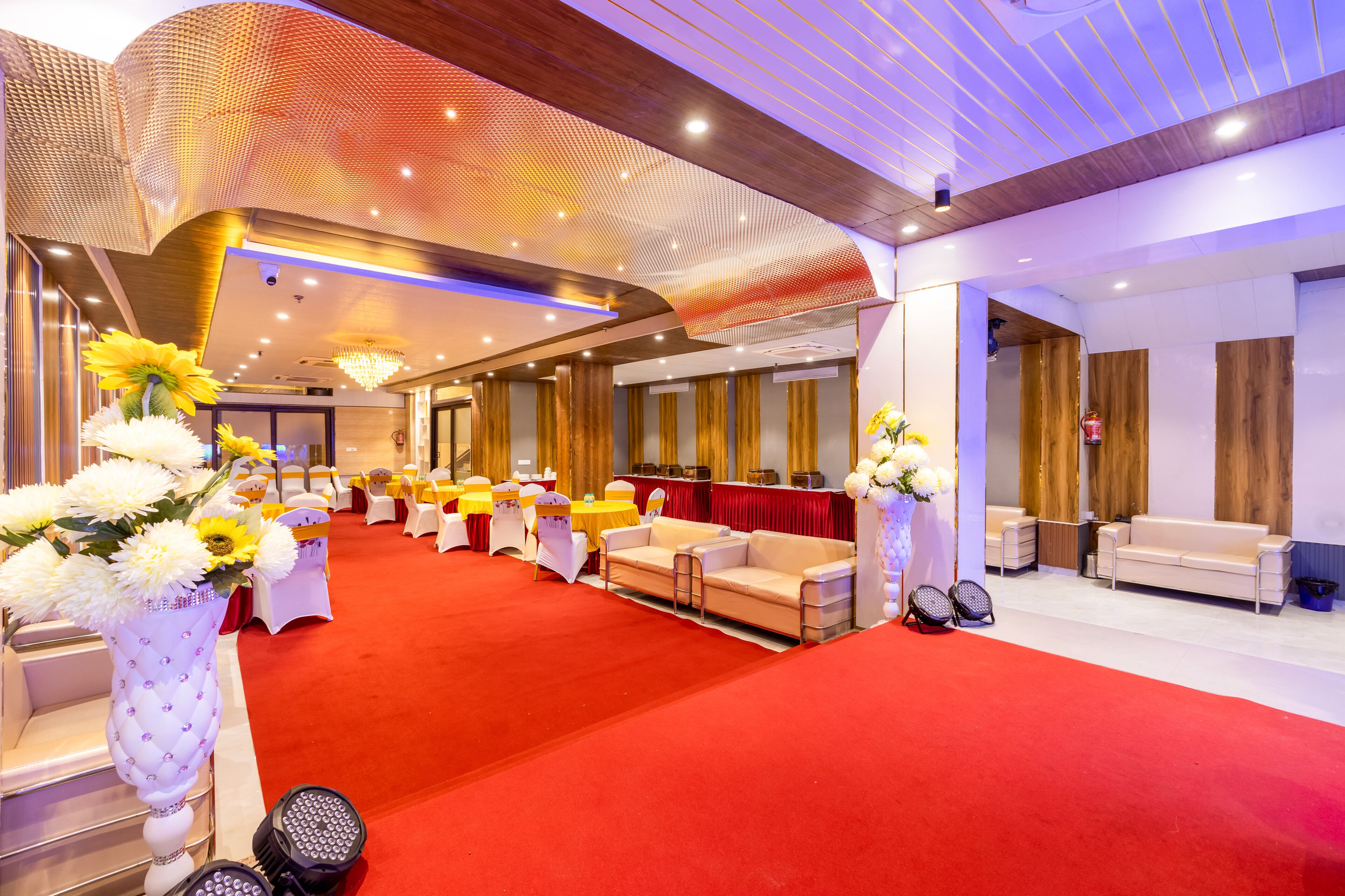 Un vestíbulo de hotel con alfombra roja, sillas blancas y una mesa de recepción.