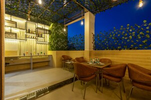 Un ristorante con zona bar, posti a sedere all'aperto e vista sulla città illuminata.