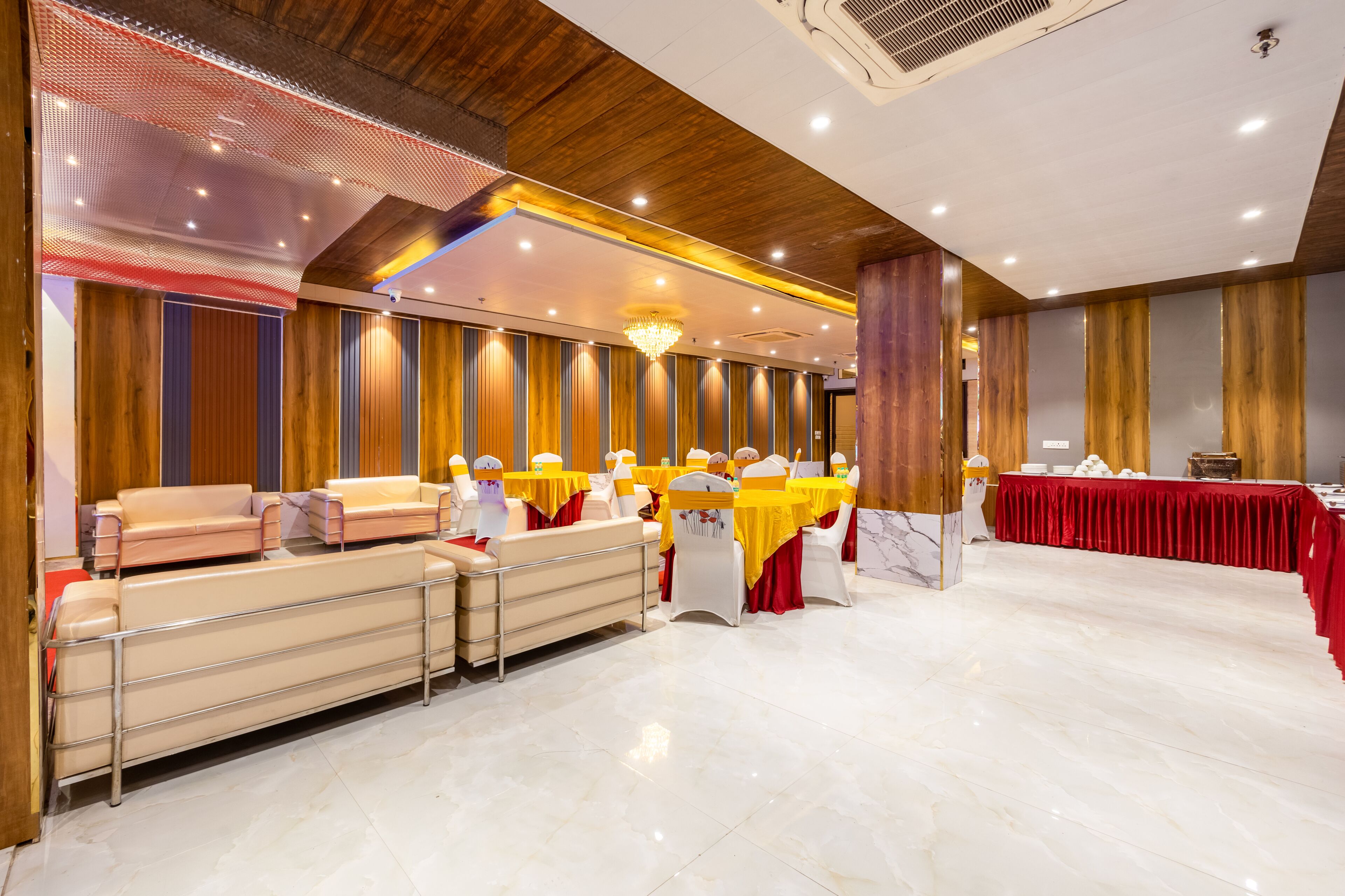 A banquet hall with tables and chairs, a long bench, and a chandelier.