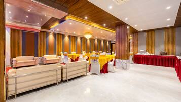 A banquet hall with tables and chairs, a long bench, and a chandelier.