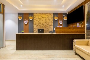 A reception desk with a laptop, a wooden counter, and a beige sofa.