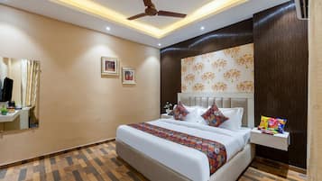 Une chambre d’hôtel moderne dotée d’un grand lit, d’un ventilateur de plafond, d’une table de chevet avec des en-cas et d’un climatiseur fixé au mur.