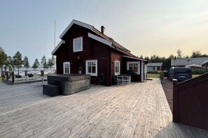 A wooden house with a deck, a hot tub, and a view of the water.