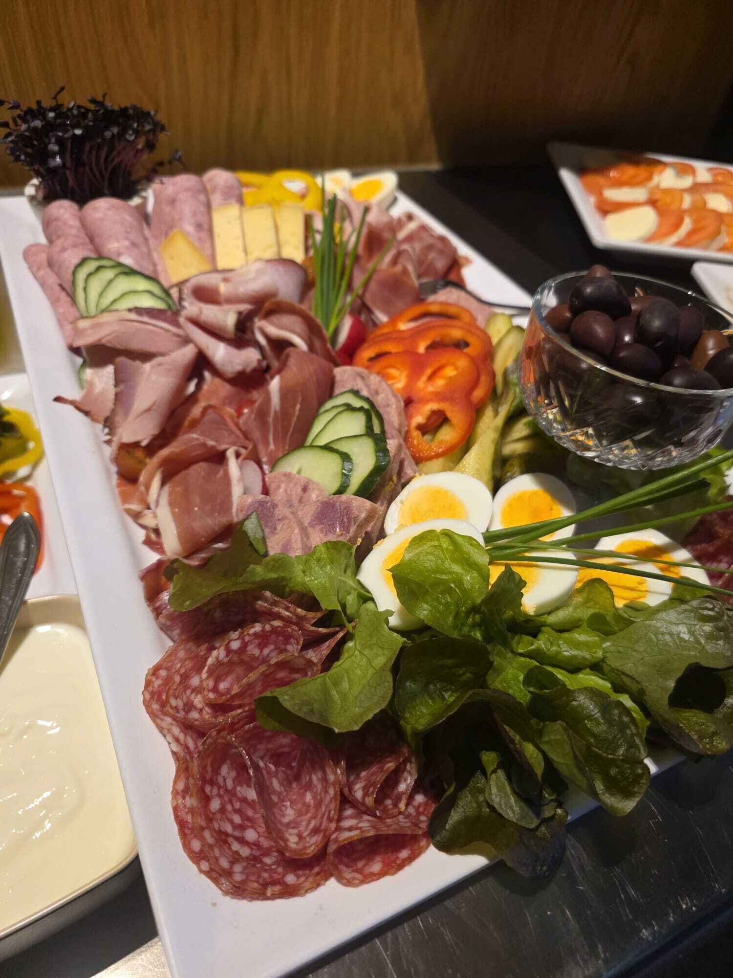 Una tabla de embutidos con diferentes carnes, quesos y verduras.