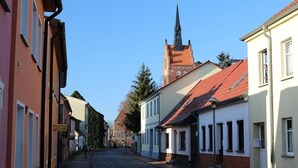 A cobblestone street lined with historic buildings, a church spire, and a clear blue sky. - Condé RE-10, Germany (Stolpe auf Usedom)