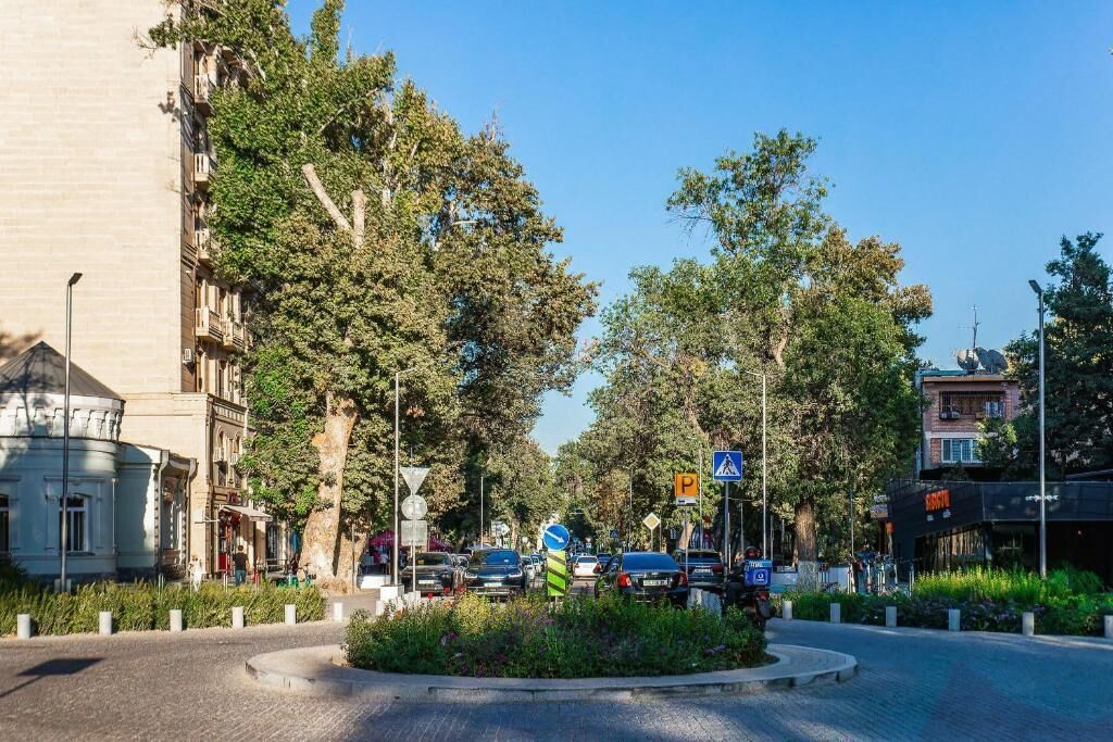 A roundabout with a central landscaped area, surrounded by trees and buildings.