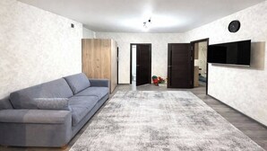 En moderne stue med en grå sofa, en stor måtte og et fladskærms-tv på væggen.