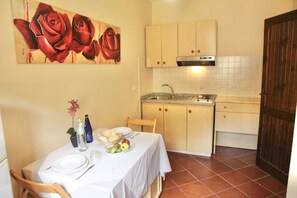 Eine kompakte Küche mit Essbereich, ausgestattet mit Tisch, Geschirr, Gläsern und Obstkorb.