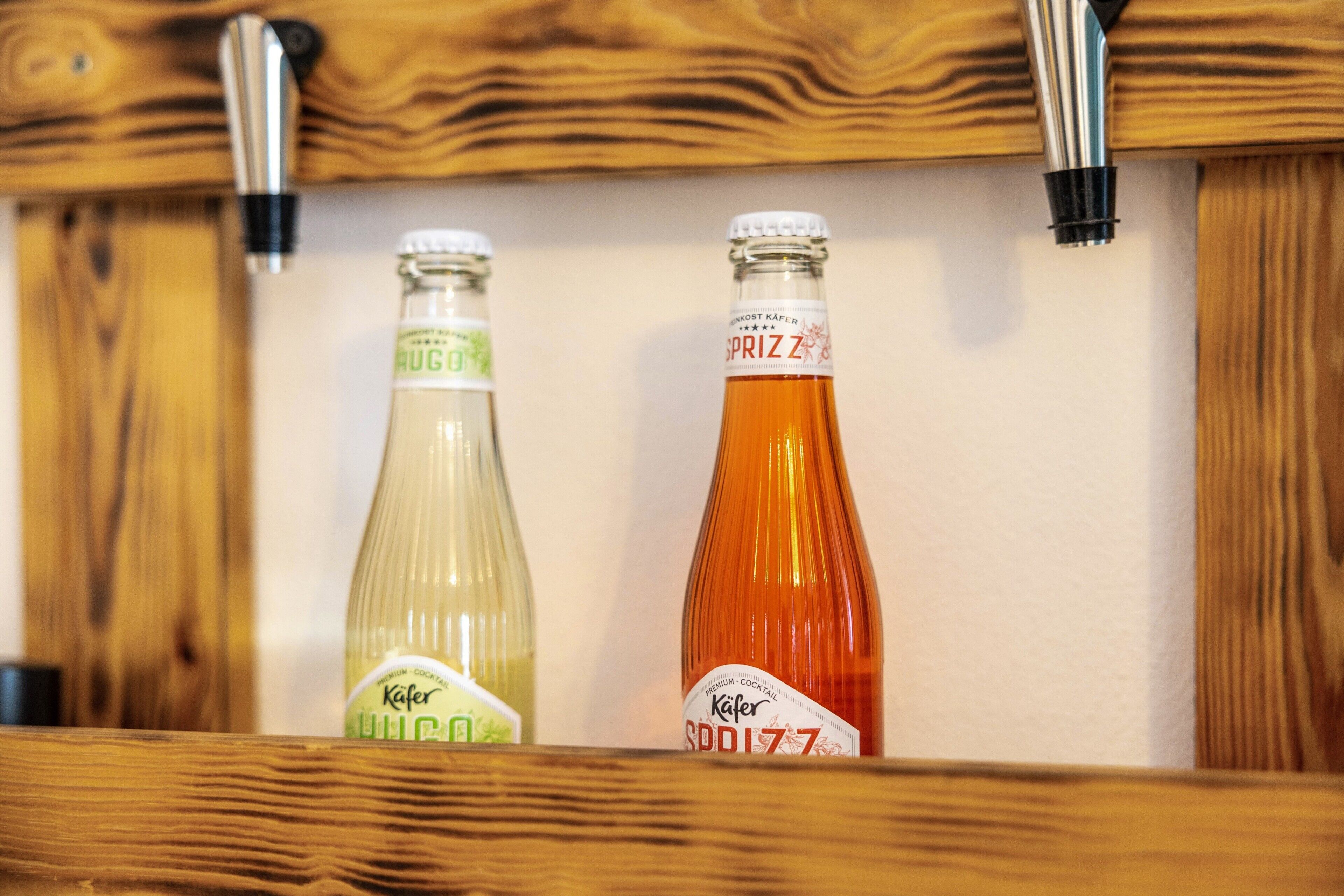 Zwei Flaschen Kafer Bier in einem Holzkabinet.