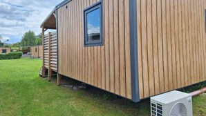 Een houten chalet met een raam en een airconditioning.