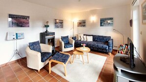 Una sala de estar con chimenea, dos sofás, una mesa de centro y un televisor.
