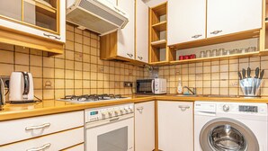 A kitchen with a stove, microwave, oven, and washing machine. - Long Stay 1BR Near Wiener Stadthalle (Vienna)