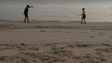 A beach with two people playing near the water.