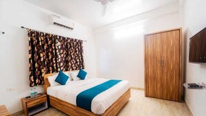 A bedroom with a wooden bed, a nightstand, a wardrobe, and a ceiling fan. - JK Valley by Shree Stays (Mahabaleshwar)