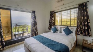 A bedroom with a bed, a window with curtains, a balcony with a chair, and a telephone on a bedside table. - JK Valley by Shree Stays (Mahabaleshwar)