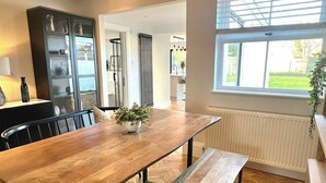 A modern kitchen with a wooden dining table, bench, and built-in appliances. - Newly Refurbished Bungalow- Large Garden- Parking (Ringwood)