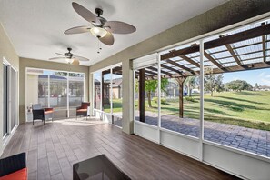 A spacious patio area with a wooden floor, large windows, and ceiling fans. - Resort Style - Spacious 5-BRM house in beautiful Davenport- Minutes to Disney (Davenport)